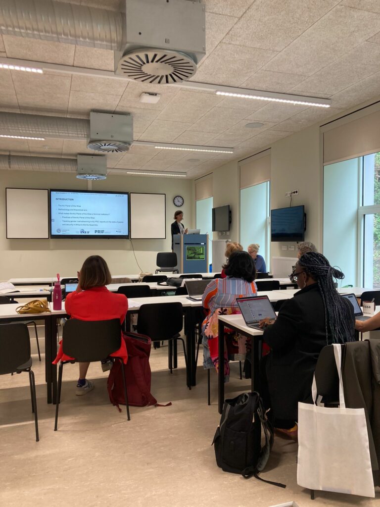 Presentation during a panel. View of a classroom with a few persons looking at a shared powerpoint presentation.