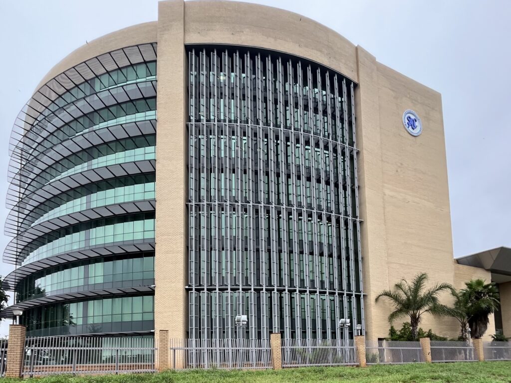 The picture depicts the SADC Headquarters. Large building from sanstone with big windows and the SADC logo on its right side.